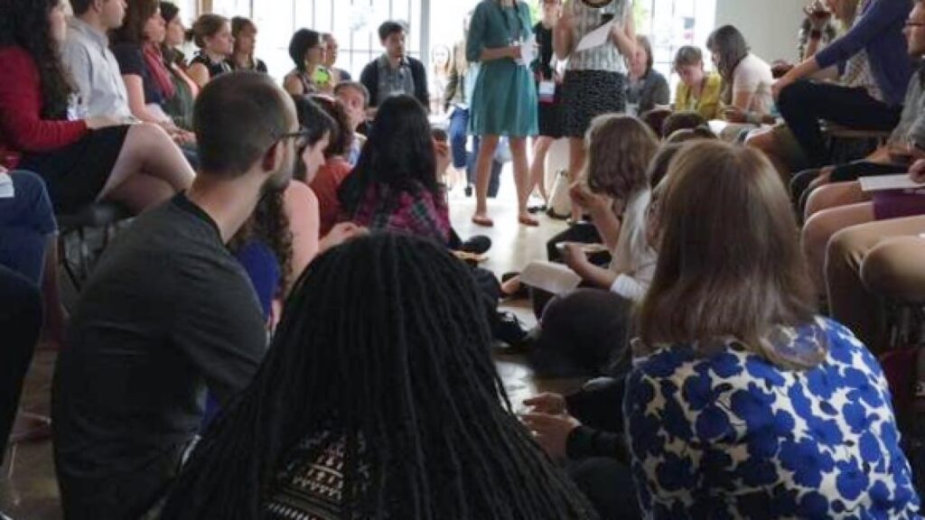 A group of people seated on chairs and on the floor